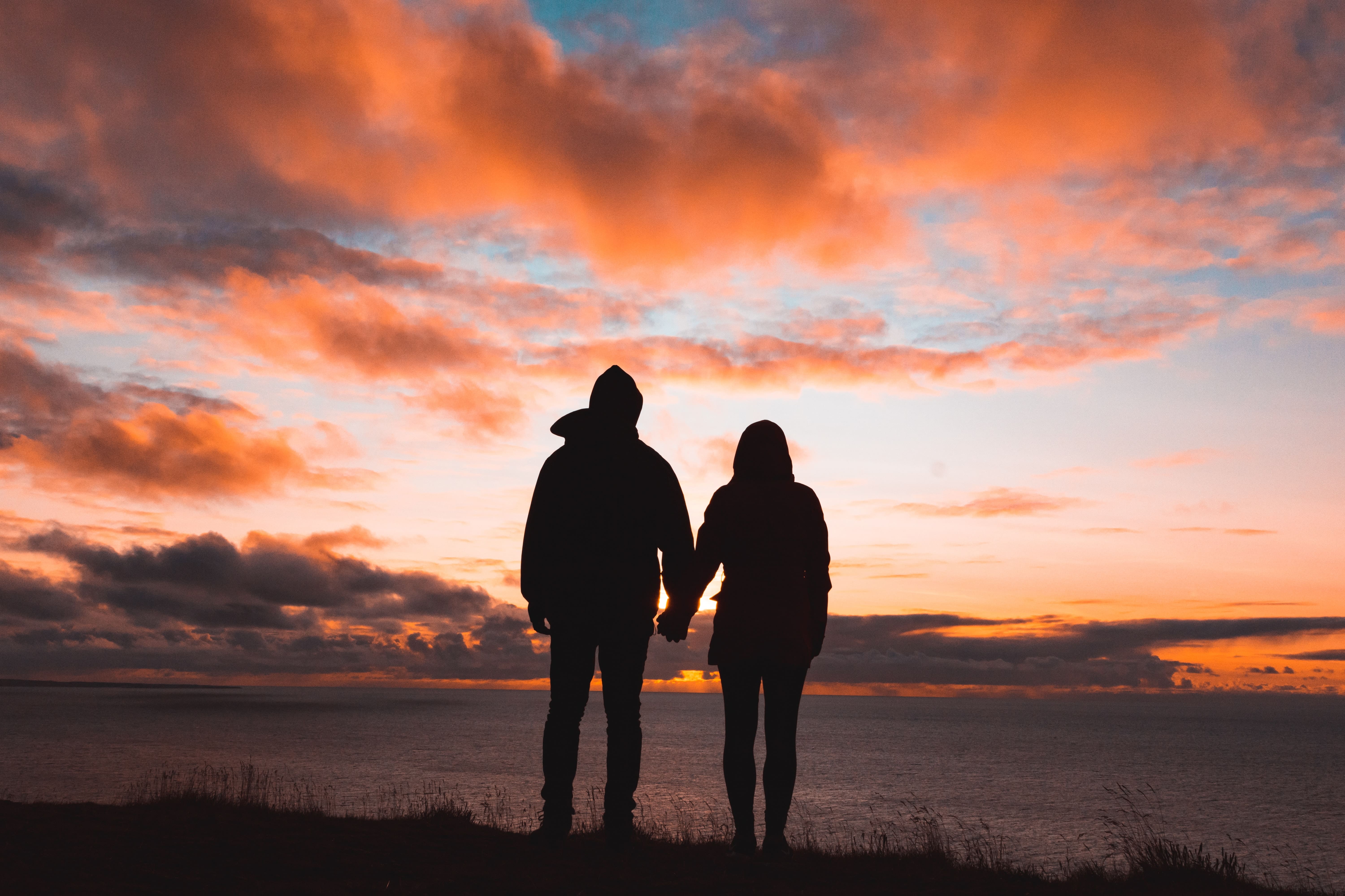 Silhouettes of a couple or partners holding hands with sunset