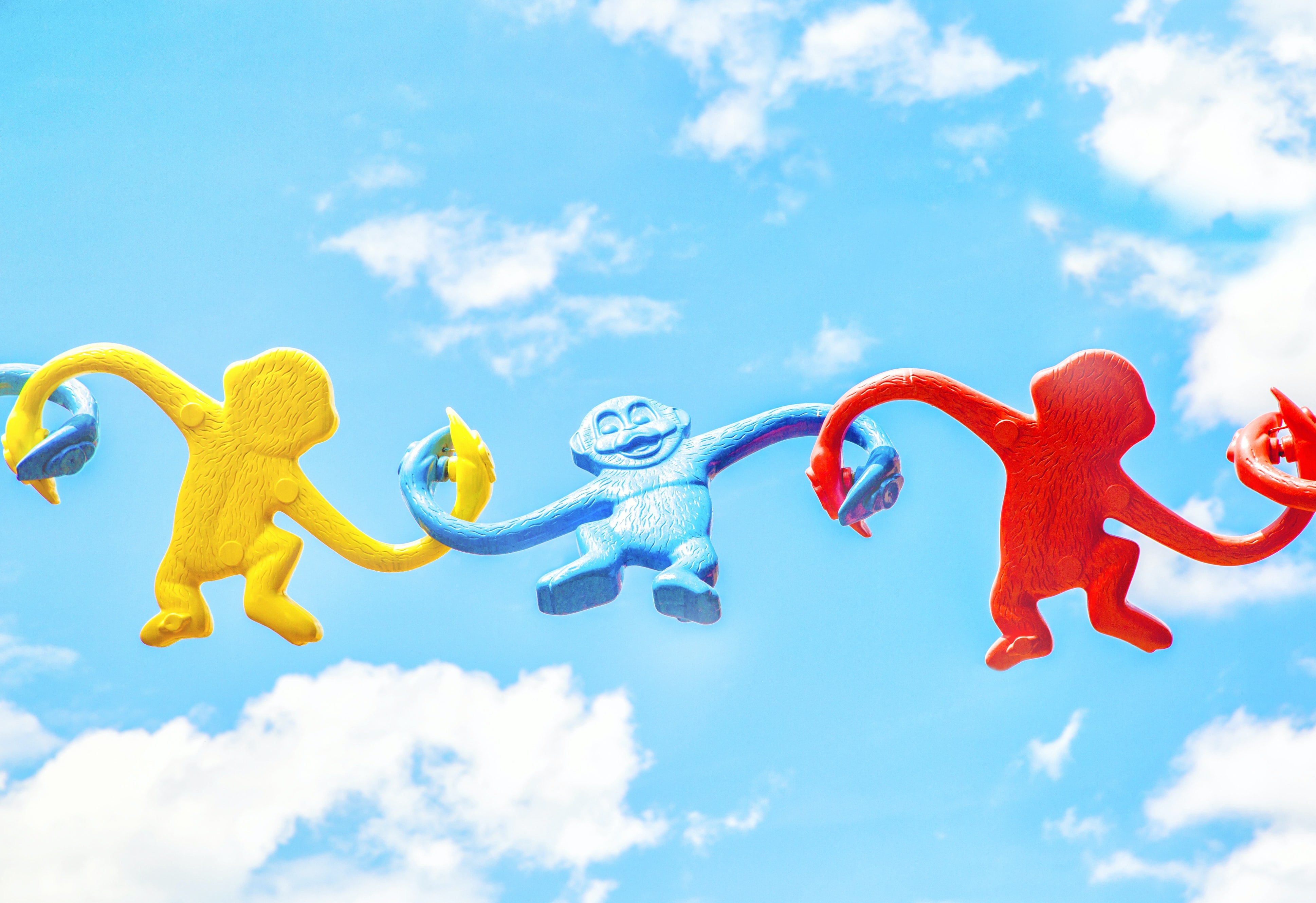 toy monkeys interconnected with blue sky