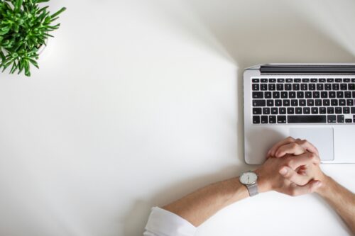 waiting by a computer hands next to a laptop