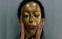 woman with gold mask in front of face