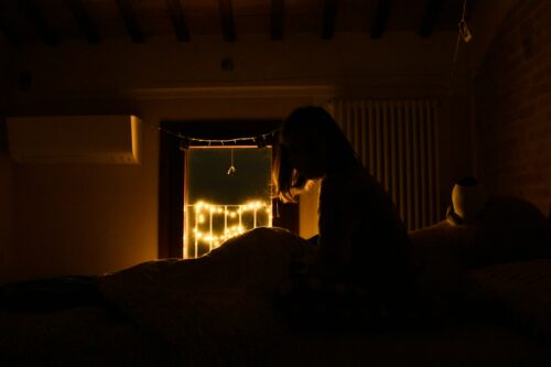 midlife woman waking in middle of night to racing thoughts and worry with fairy lights outside